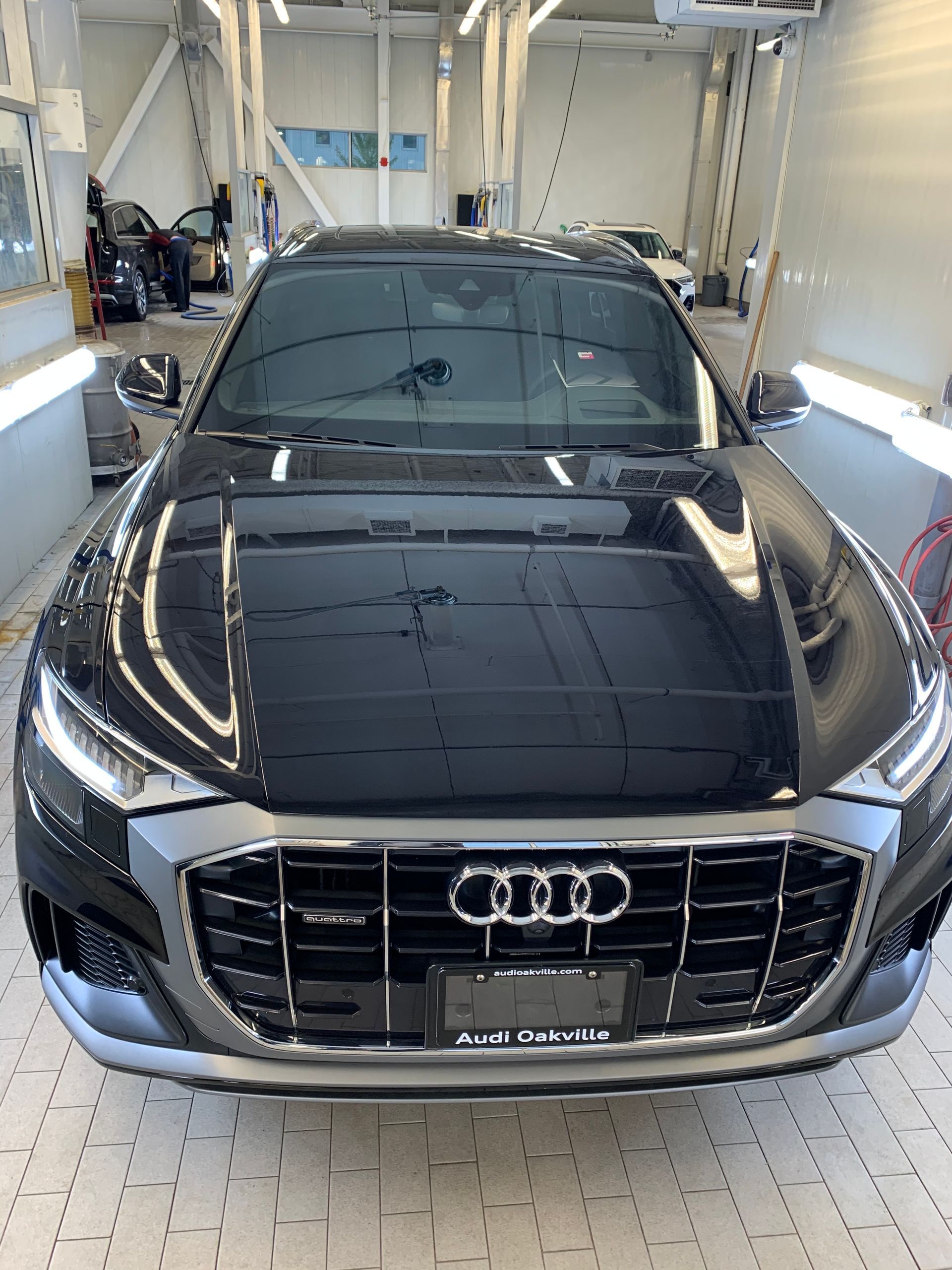 A black Audi SUV parked inside a well-lit car dealership service bay.