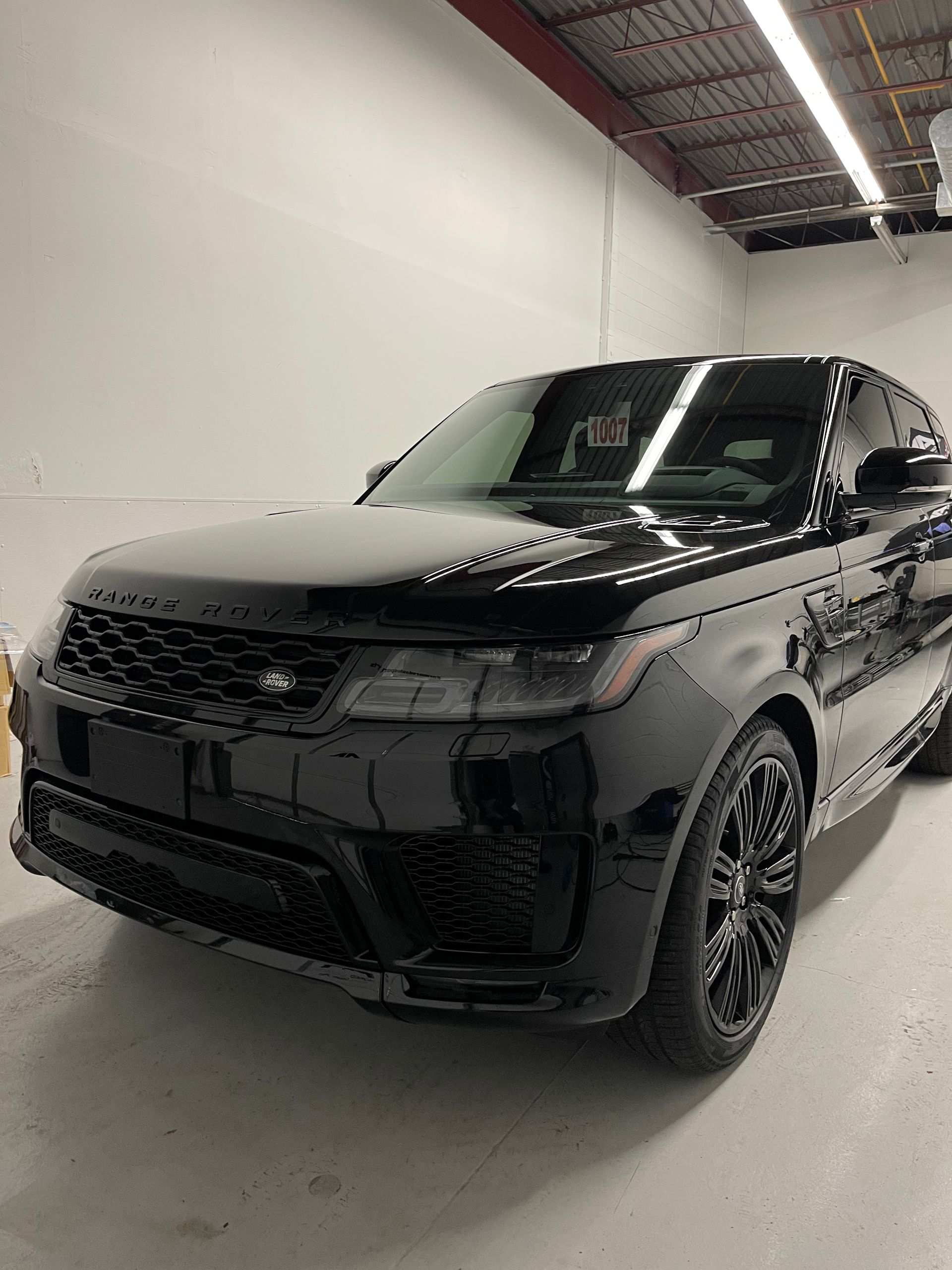 A sleek black Range Rover Sport SUV parked inside a garage with bright overhead lighting.