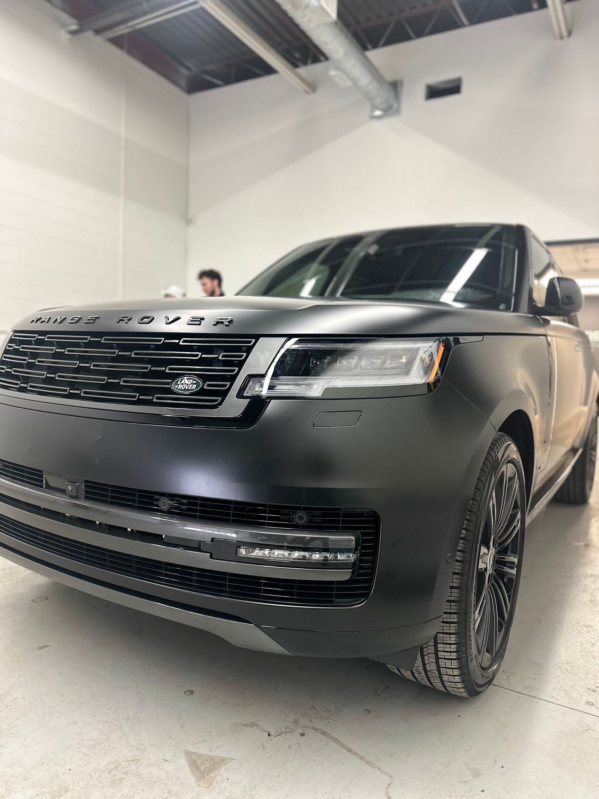 A matte black Range Rover SUV parked in a garage, shown from a low-angle, front-quarter view.