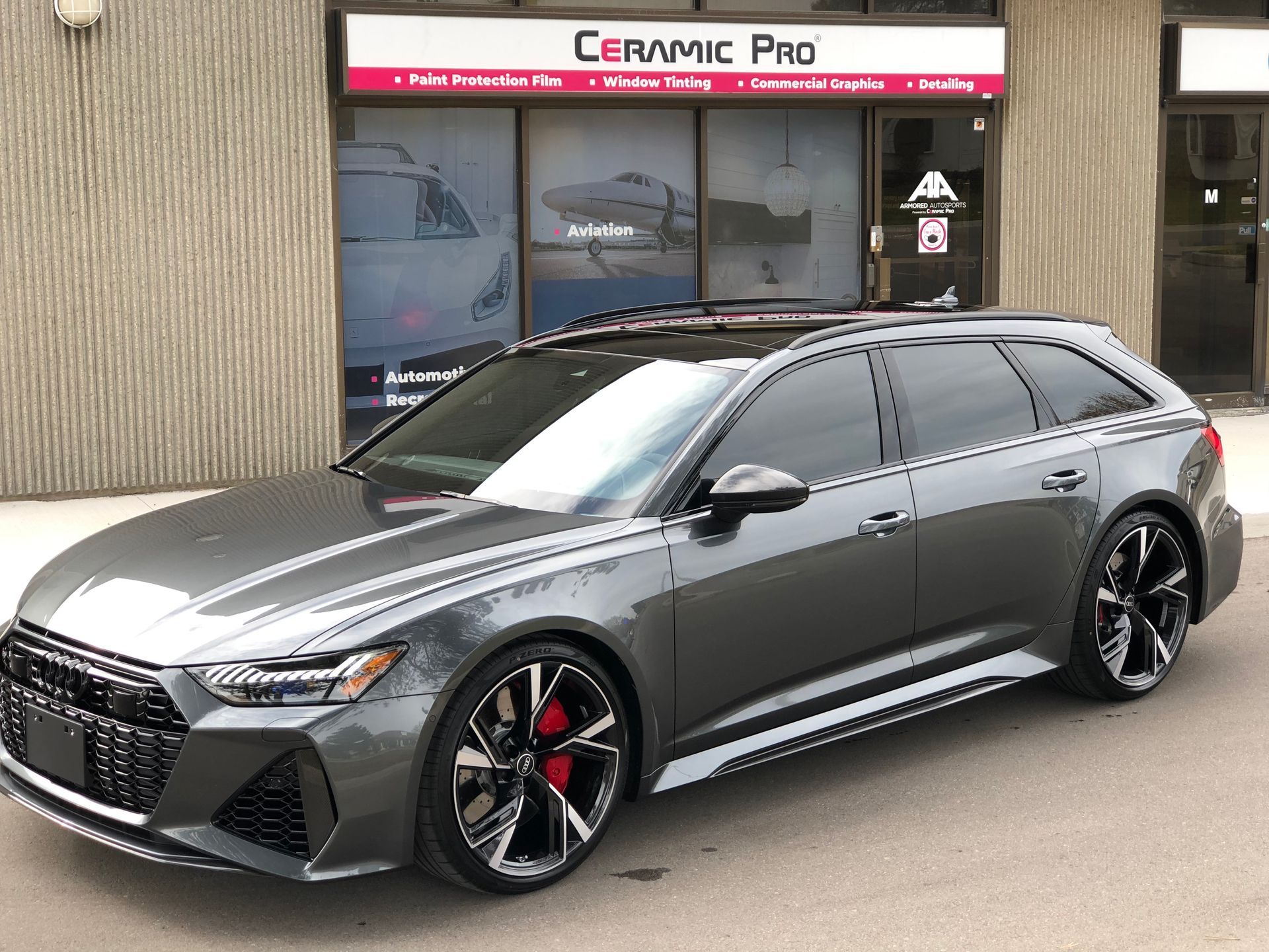 A gray Audi RS6 Avant wagon parked outside a Ceramic Pro shop.