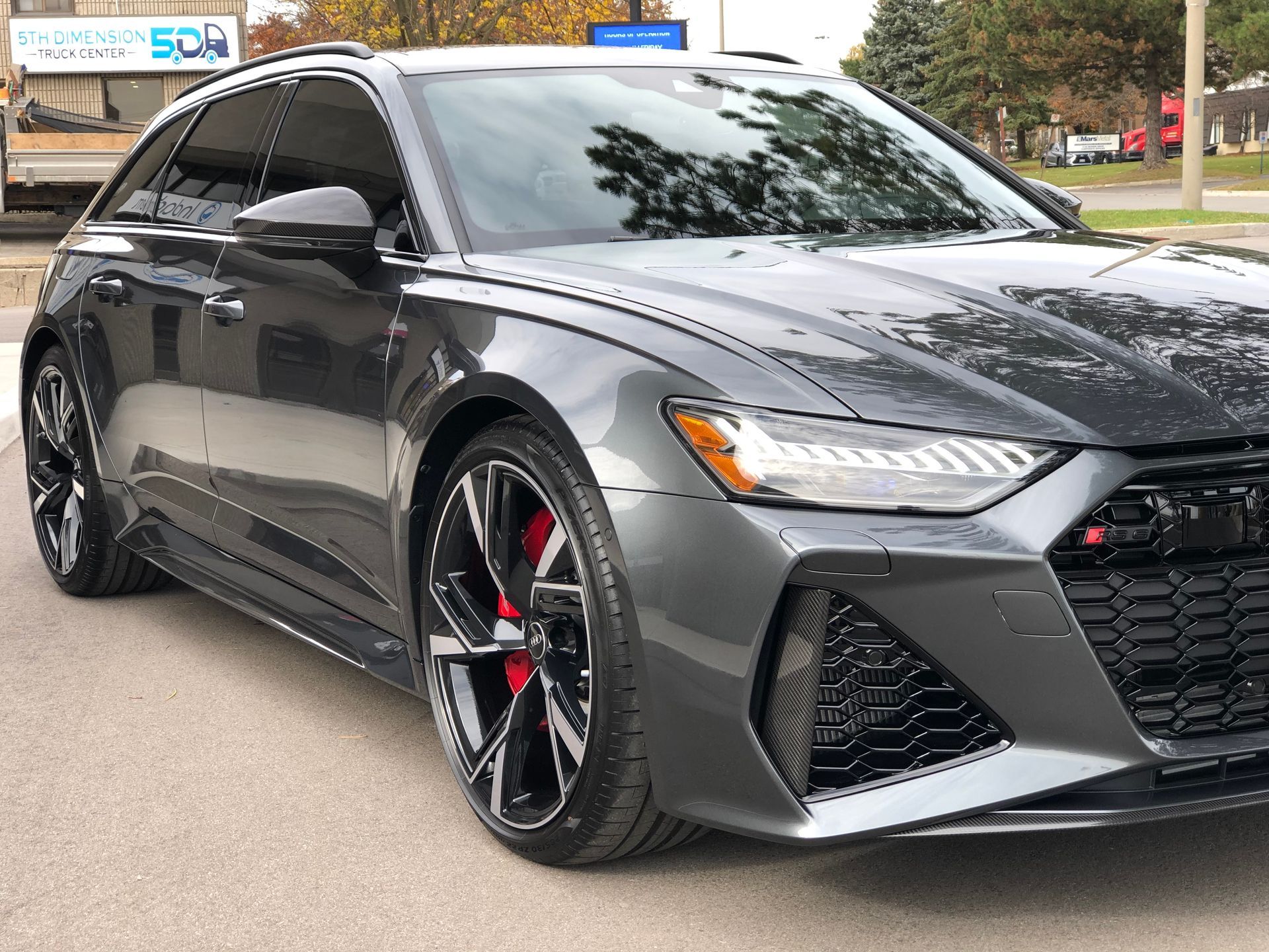 A dark gray Audi RS 6 Avant parked outdoors, featuring sporty alloy wheels, red brake calipers, and a sleek, modern design.