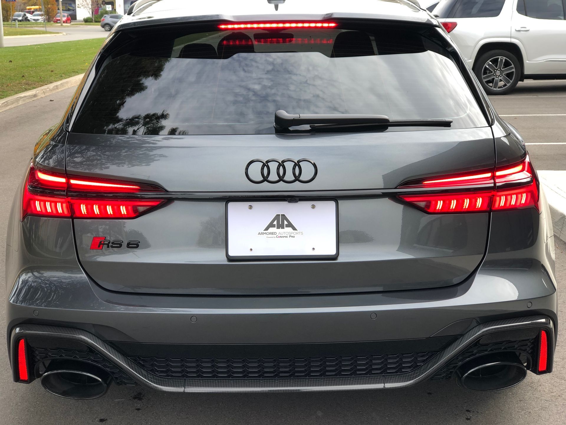 A grey Audi RS 6 Avant parked outdoors, showing its rear, LED taillights, black emblems, and dual exhaust tips.