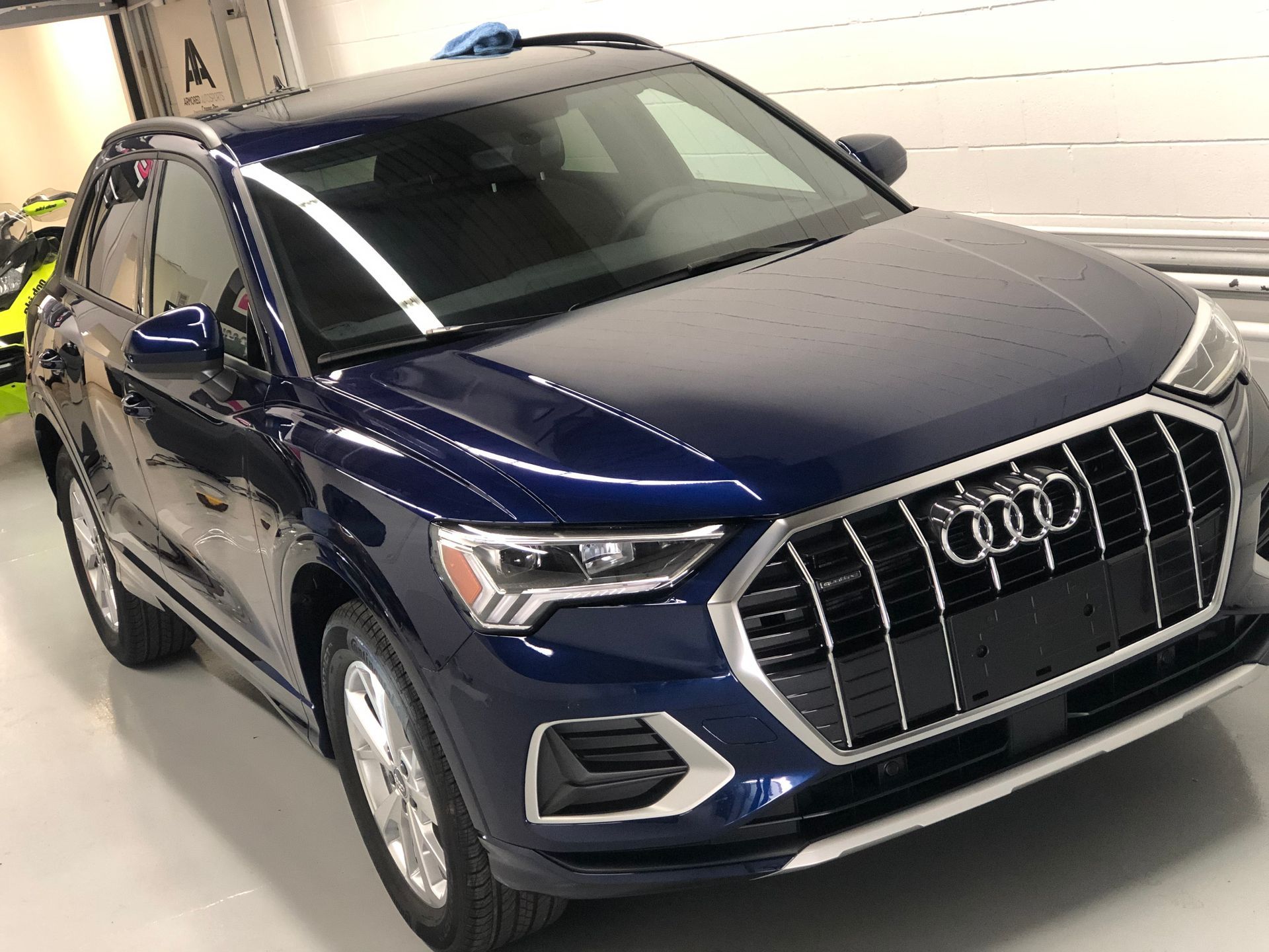 A dark blue Audi Q3 SUV parked in a garage with reflective lighting.