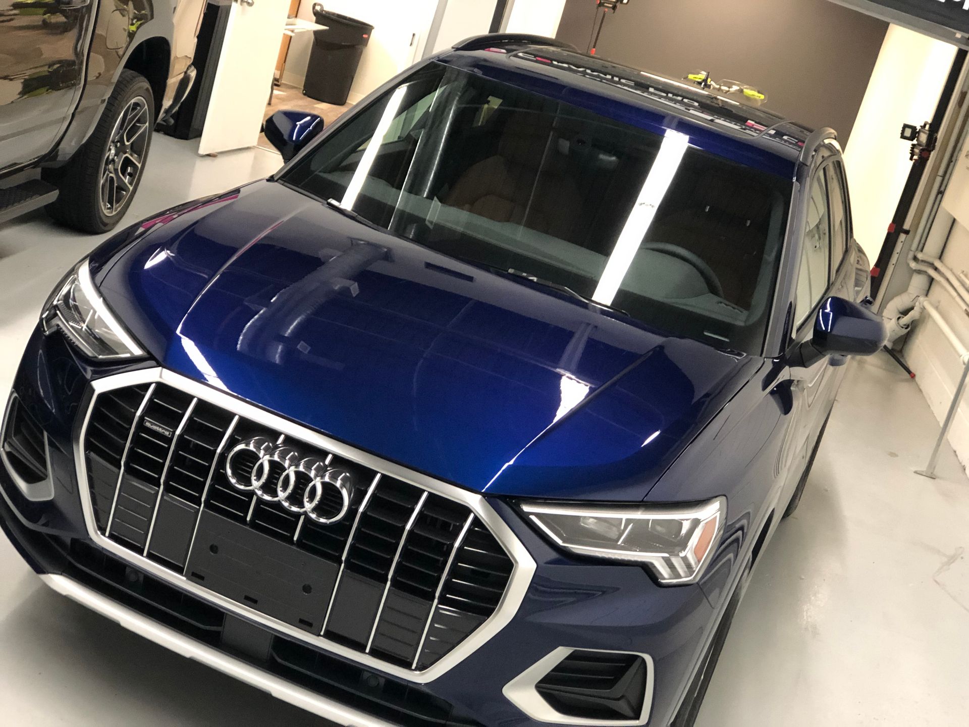 A front view of a dark blue Audi Q3 SUV parked inside a garage.