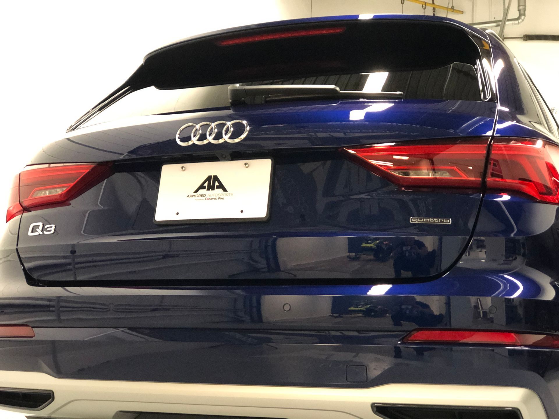 Rear view of a dark blue Audi Q3 SUV, featuring the brand emblem, model badge, and a dealer license plate.