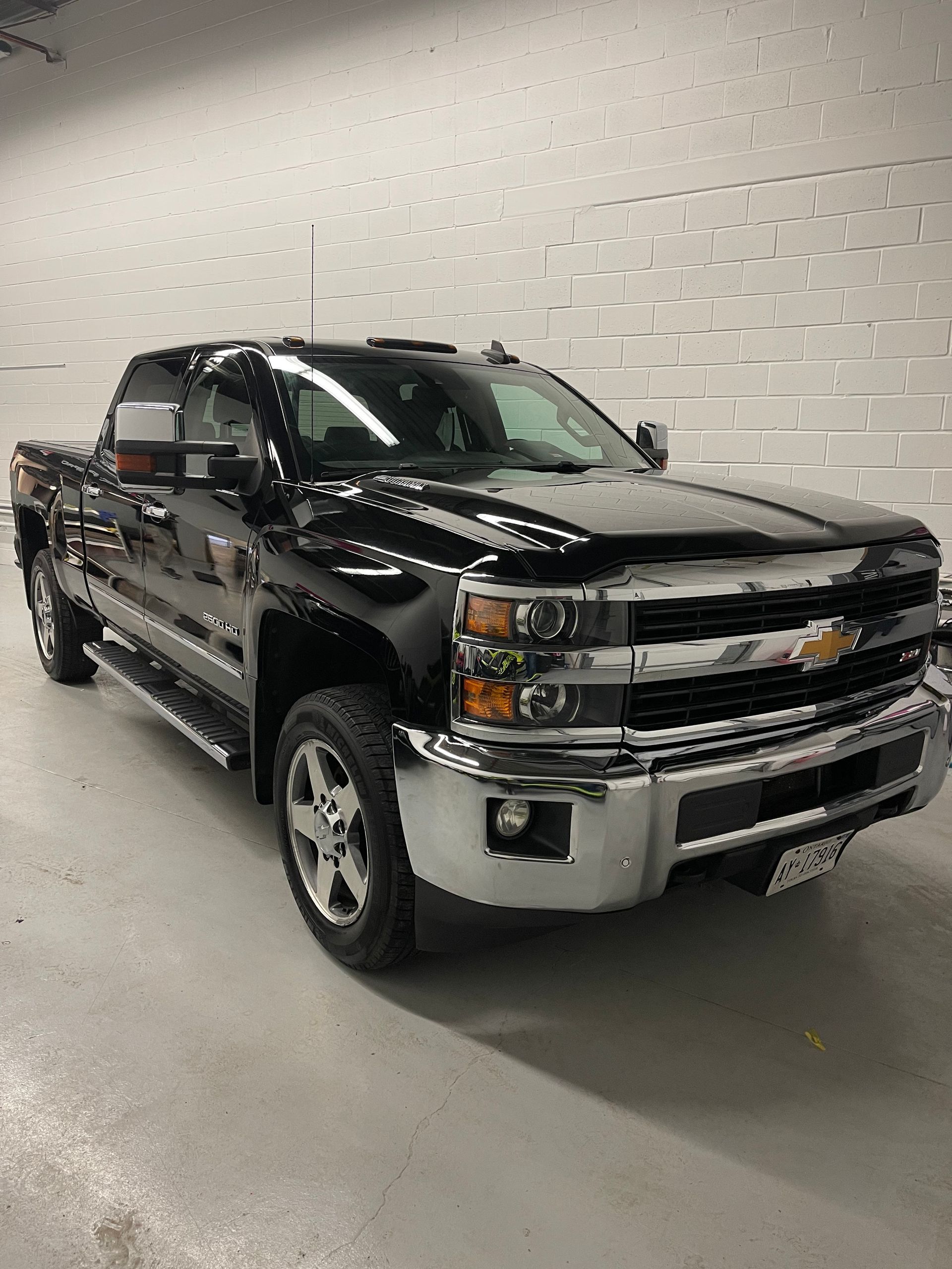 A black Chevrolet Silverado pickup truck parked indoors on a concrete floor in front of a white brick wall.