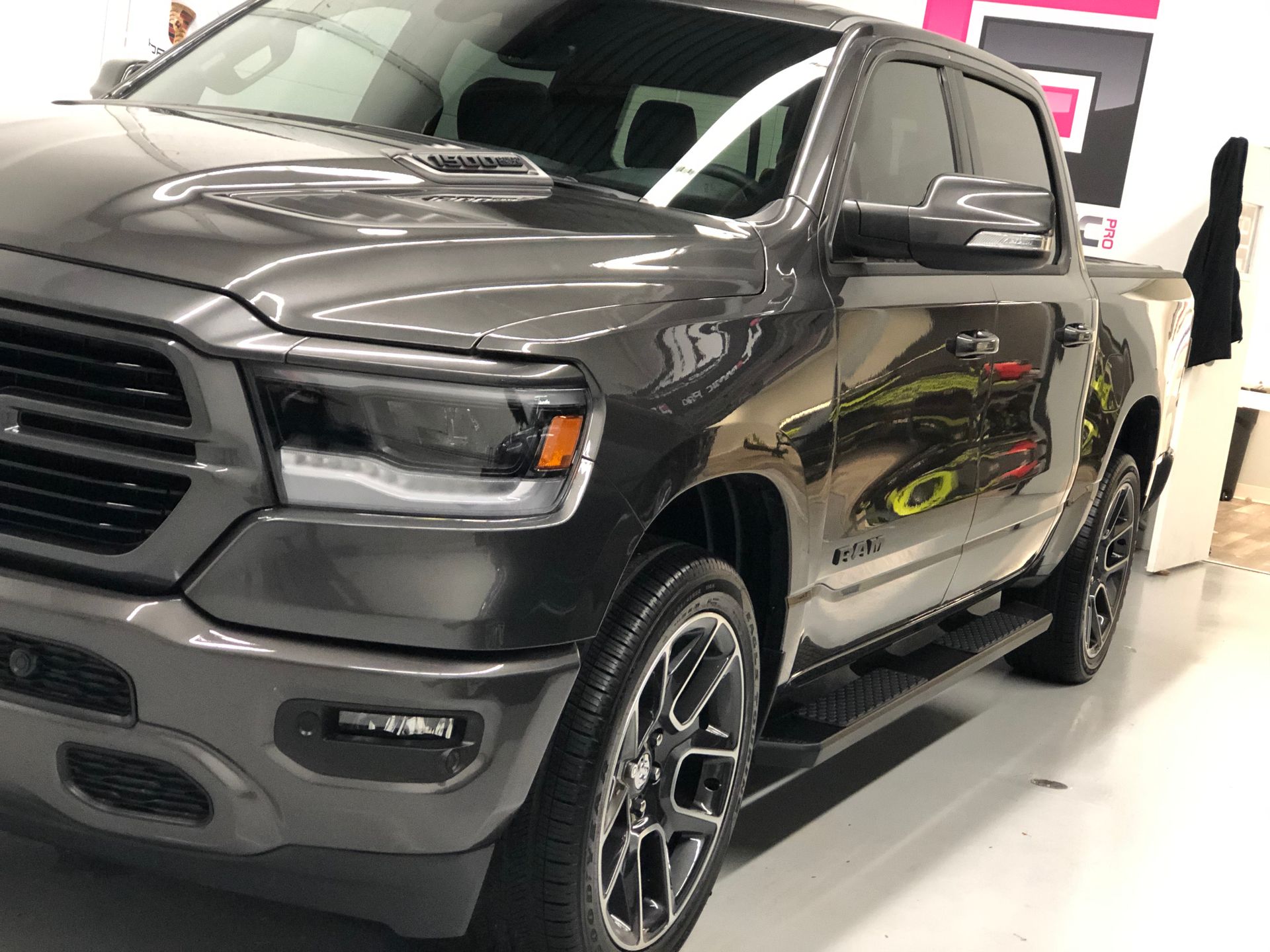 A dark gray Ram pickup truck parked indoors on a light-colored floor, viewed from the front passenger side.
