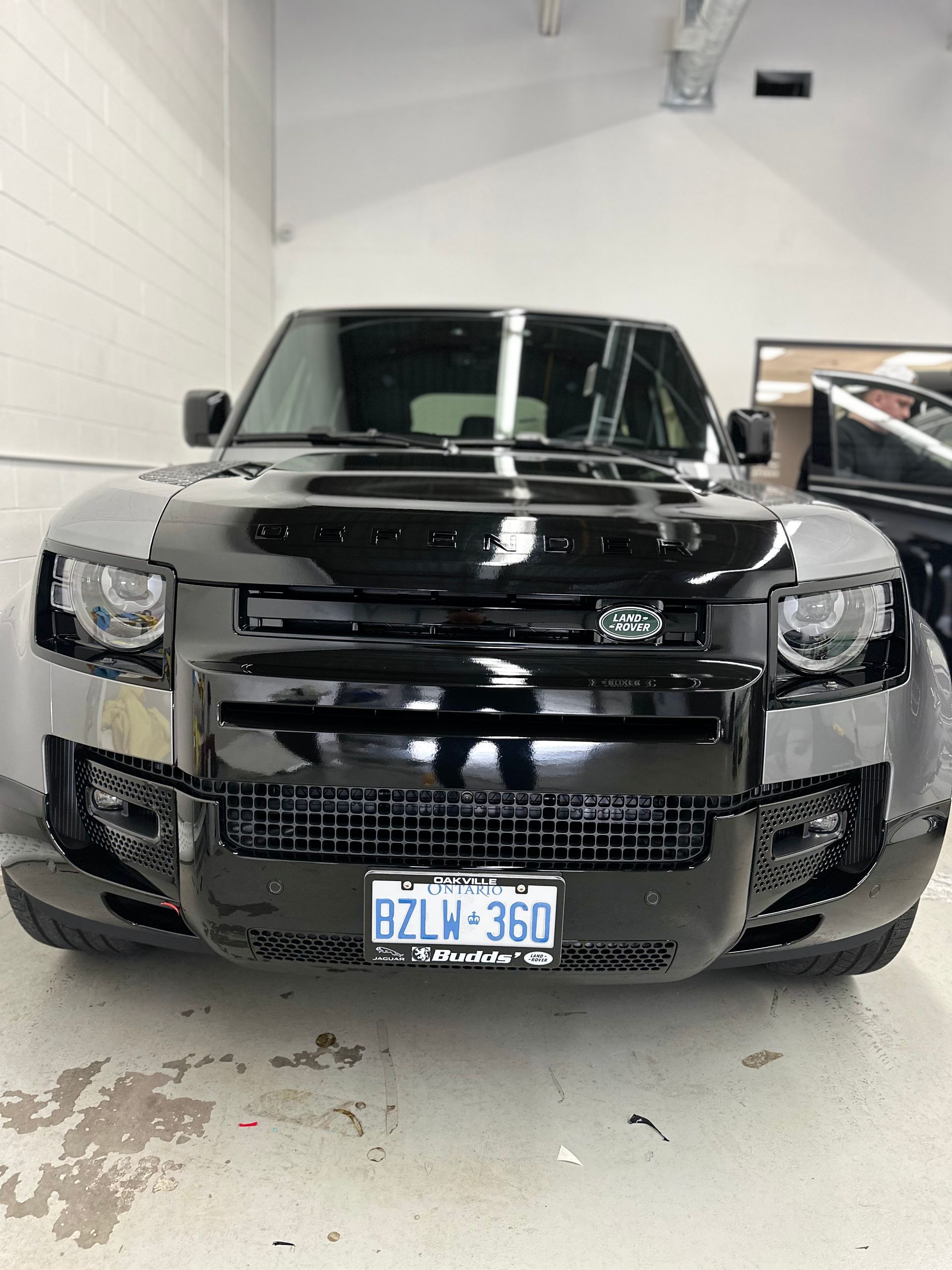 A black Land Rover Defender parked inside a shop with a visible Ontario license plate.