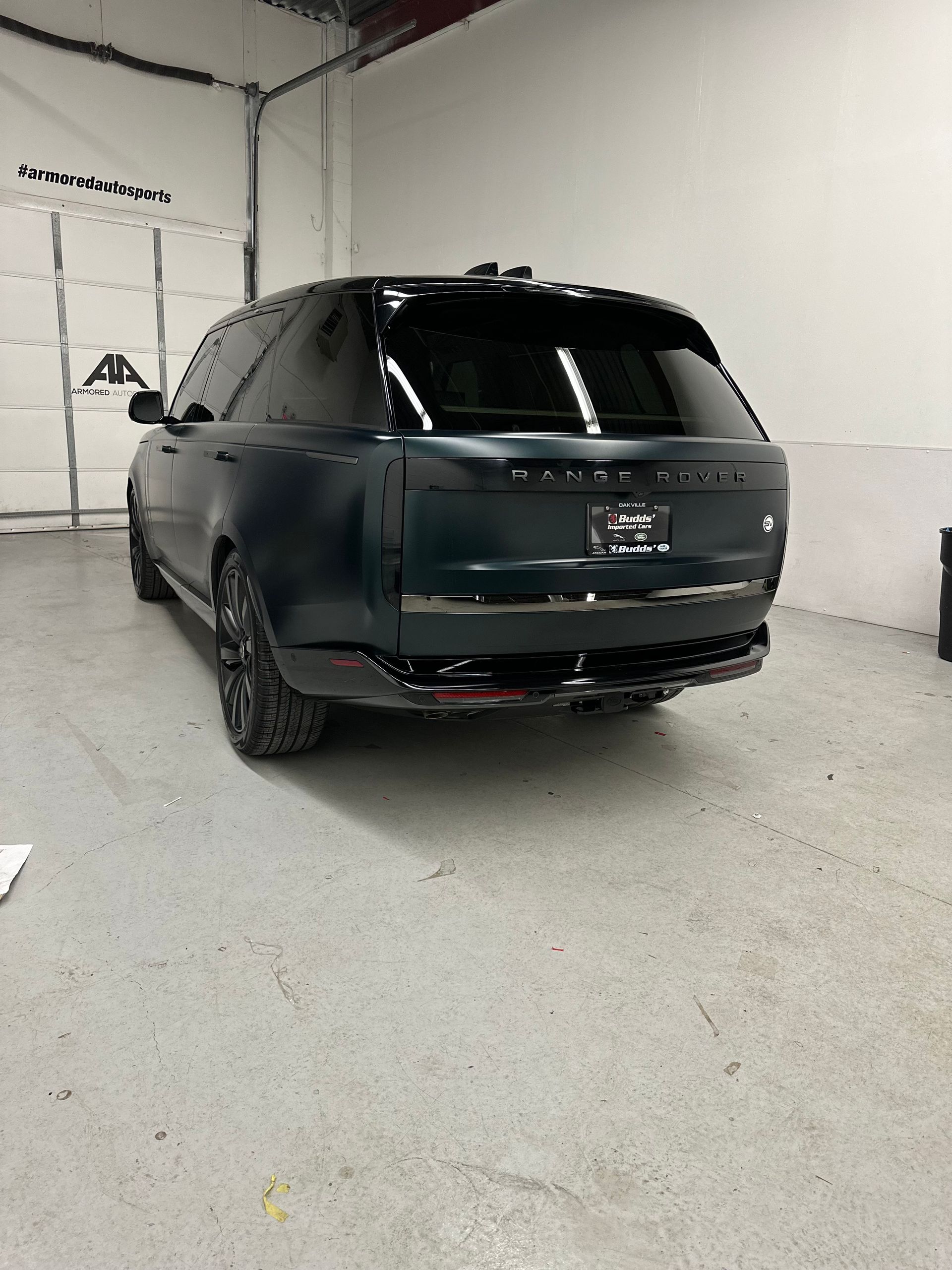 A dark-colored Range Rover SUV parked at an angle inside a white-walled garage with a concrete floor.