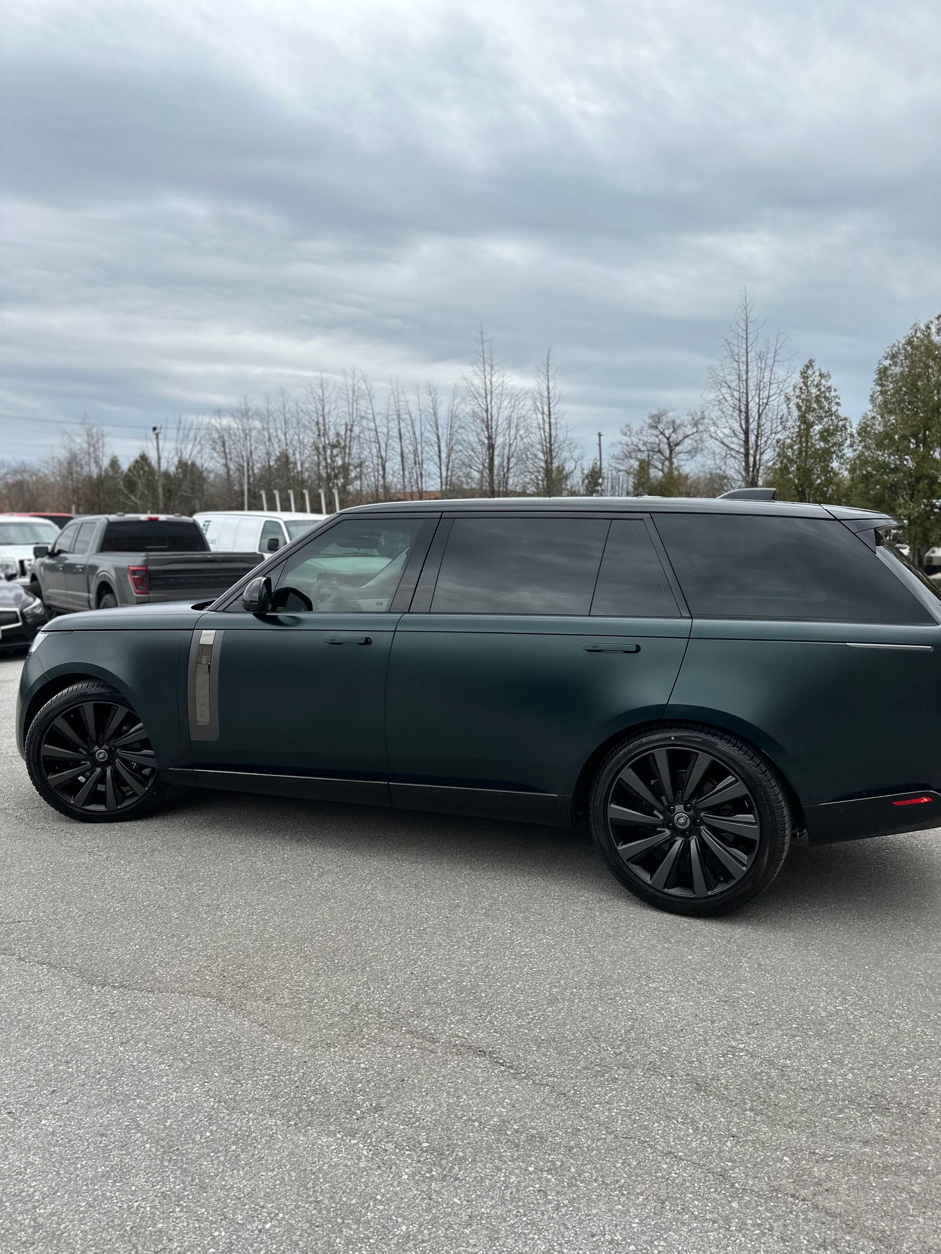 A dark green Range Rover parked in an outdoor gravel lot under an overcast sky.
