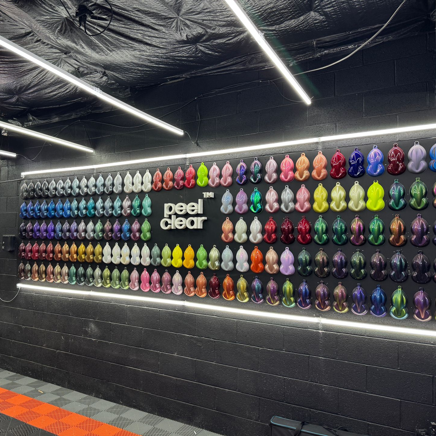 Wall display of colorful paint samples for cars. Various colors: red, green, blue, purple, and more.