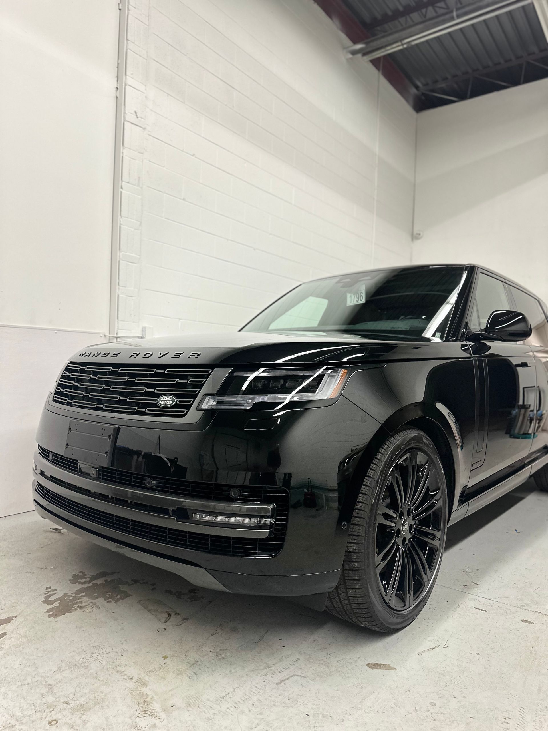 A sleek black Range Rover parked inside a bright, white-walled garage.