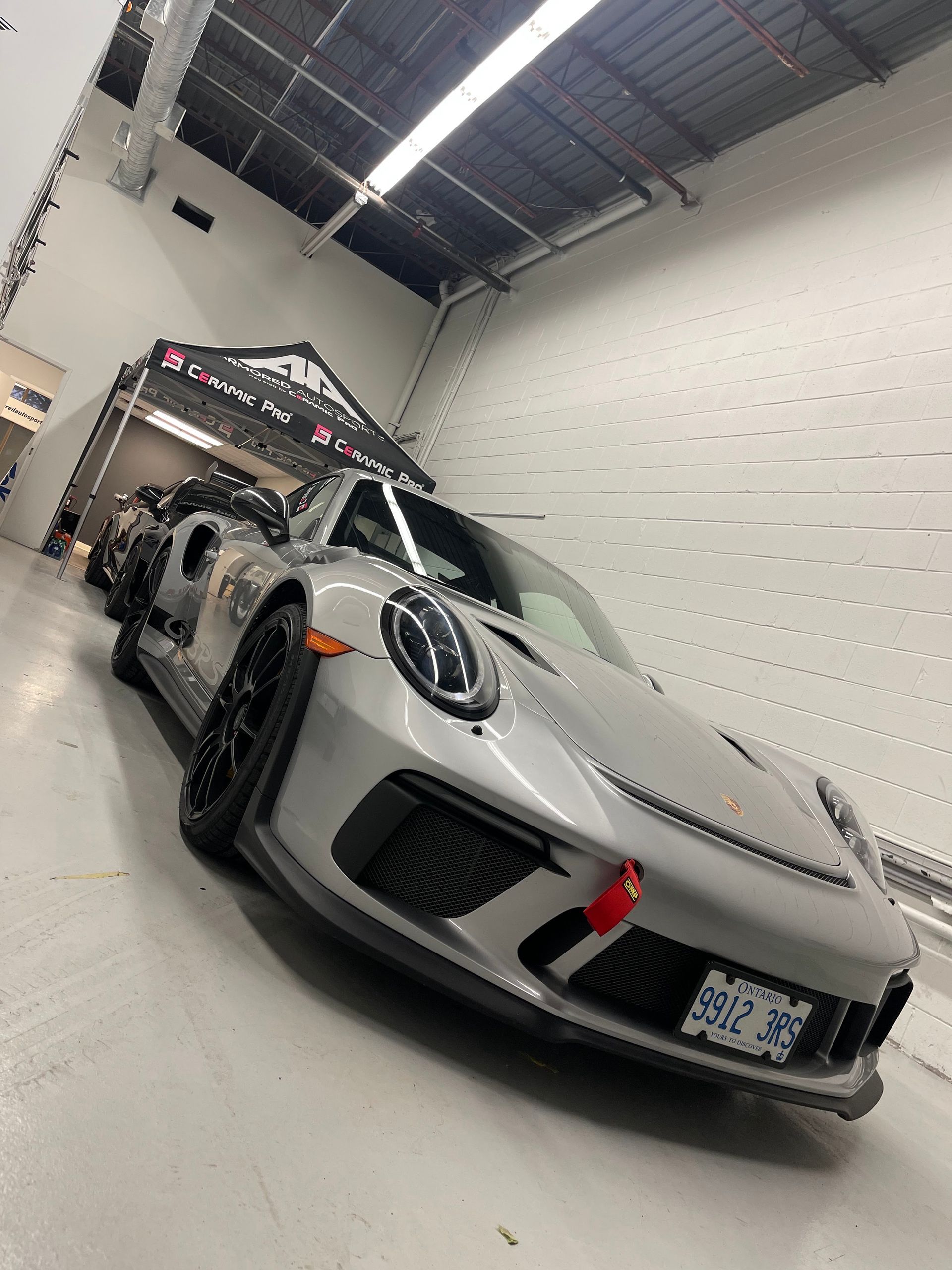 A silver Porsche 911 GT3 RS parked in a brightly lit industrial garage or showroom.