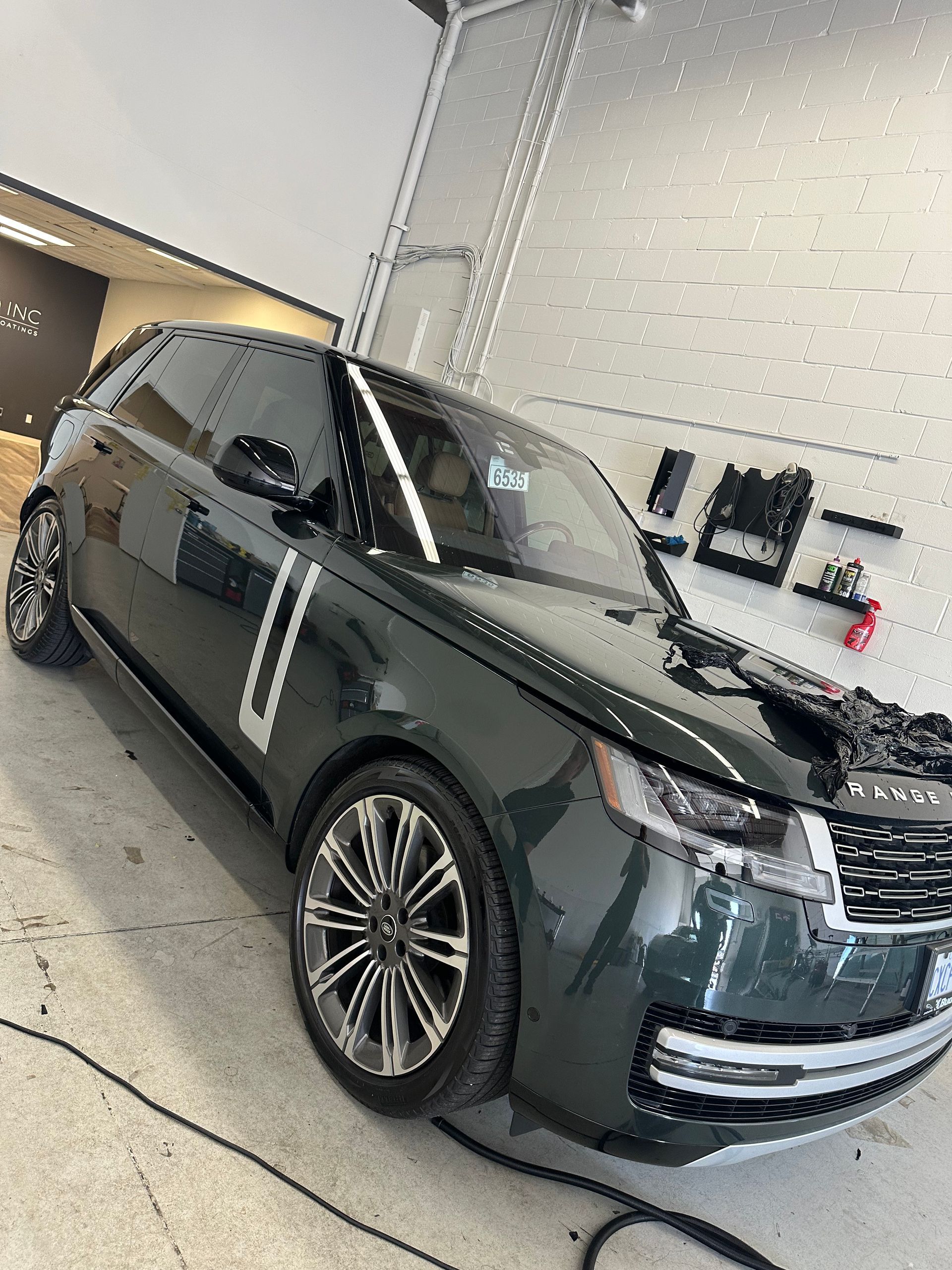 A dark green Range Rover parked inside a bright, clean automotive garage.