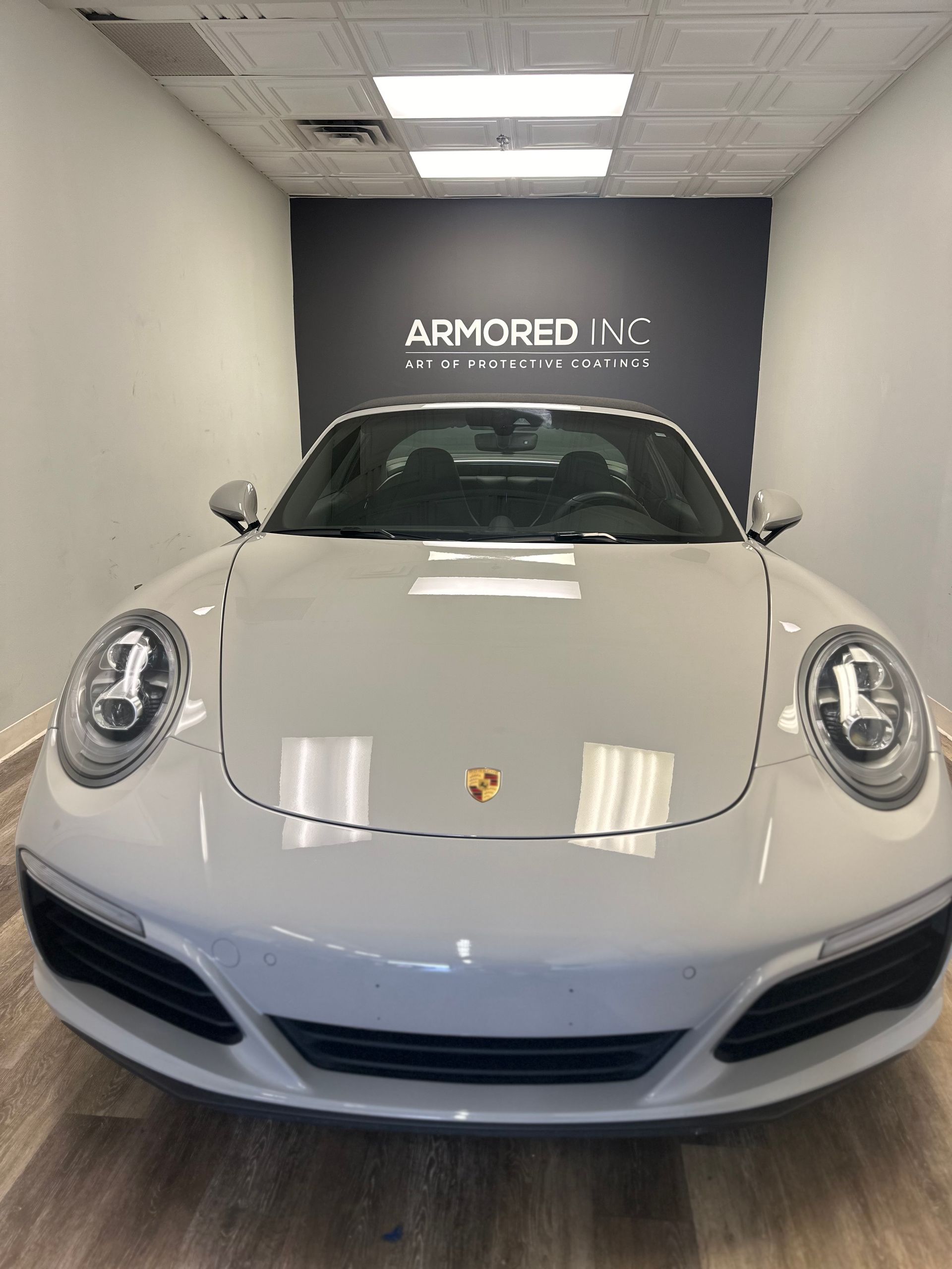 A grey Porsche parked inside a studio with an 
