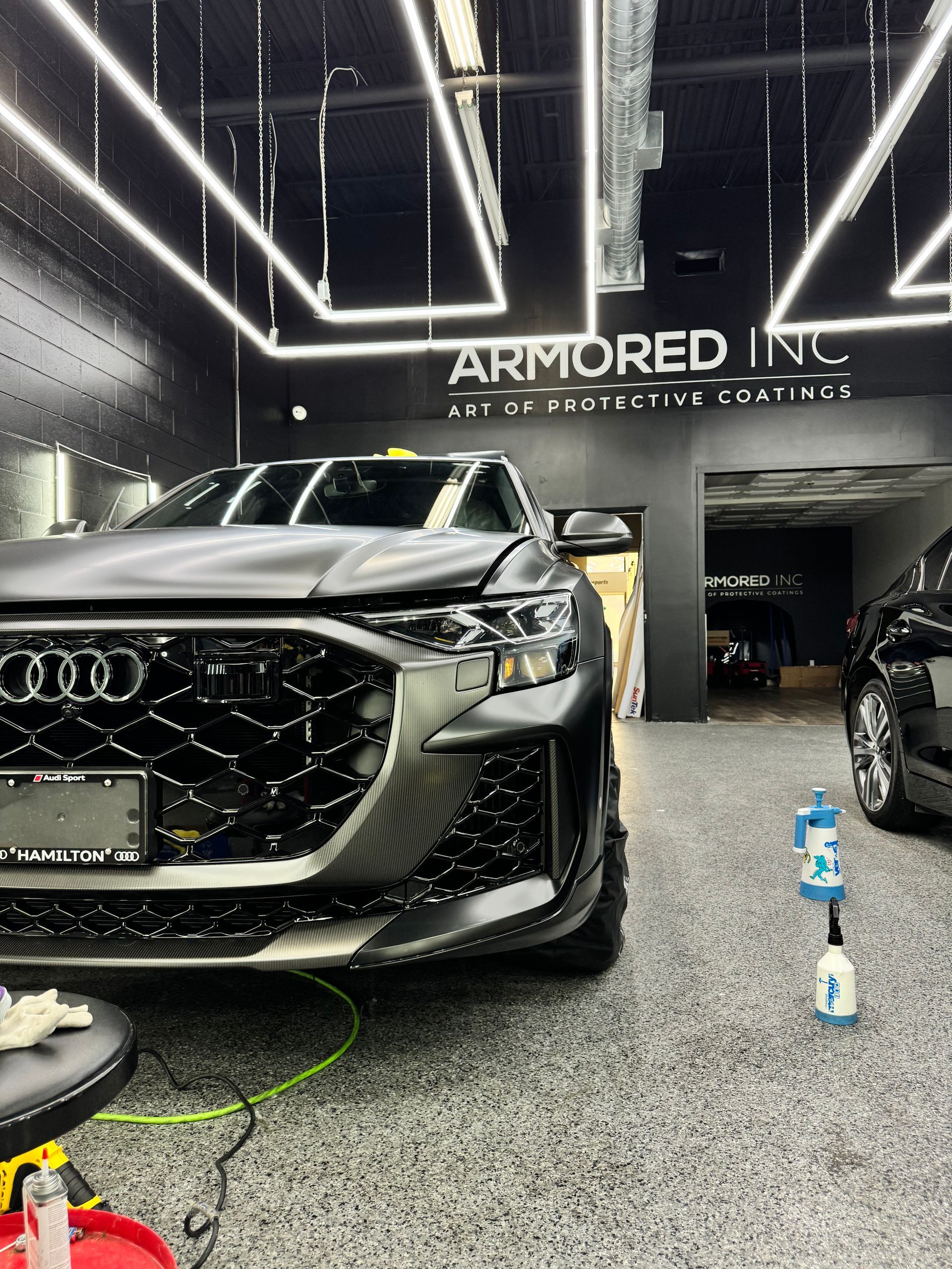 A dark-colored Audi sits in an auto detailing shop with 