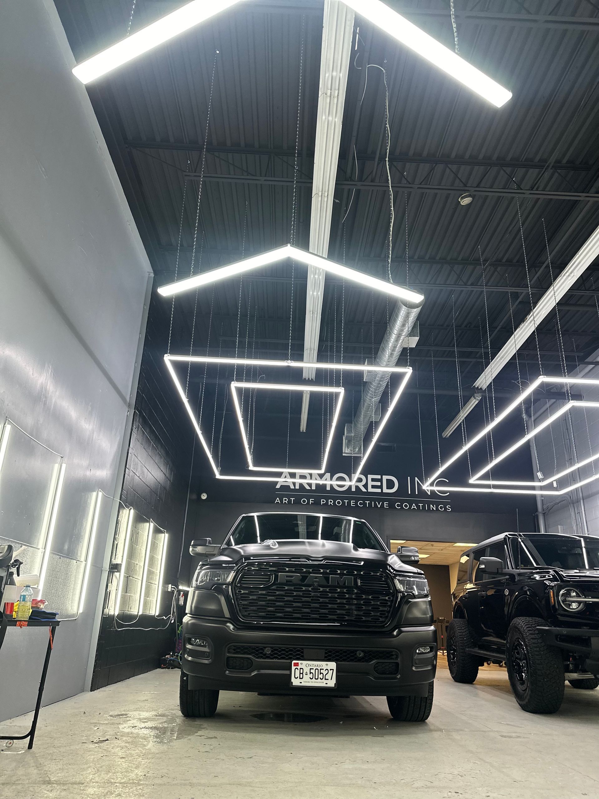 Black trucks parked in a modern, industrial-style garage with geometric LED ceiling lights and 