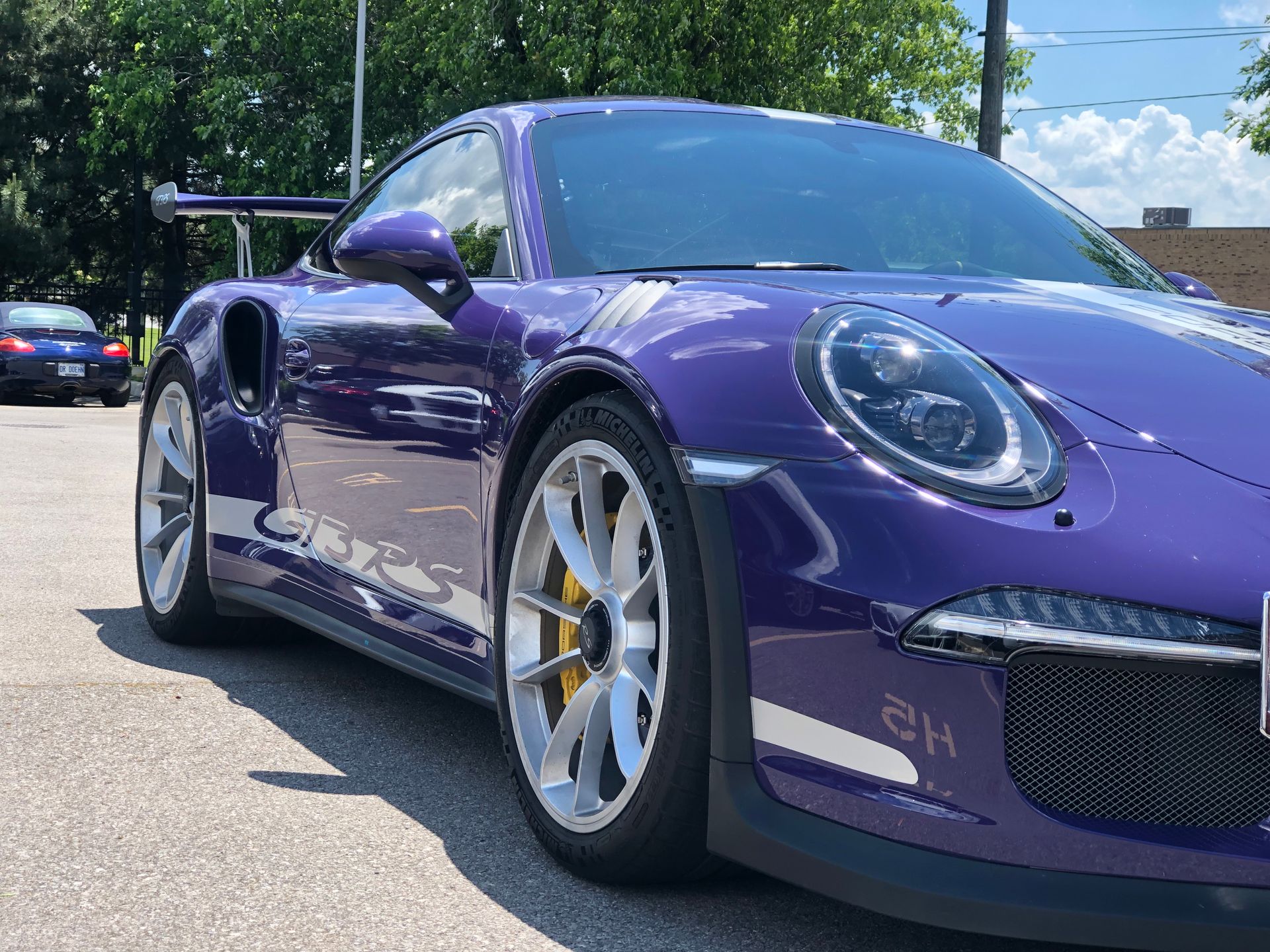 A bright purple Porsche 911 GT3 RS parked outdoors on a sunny day.
