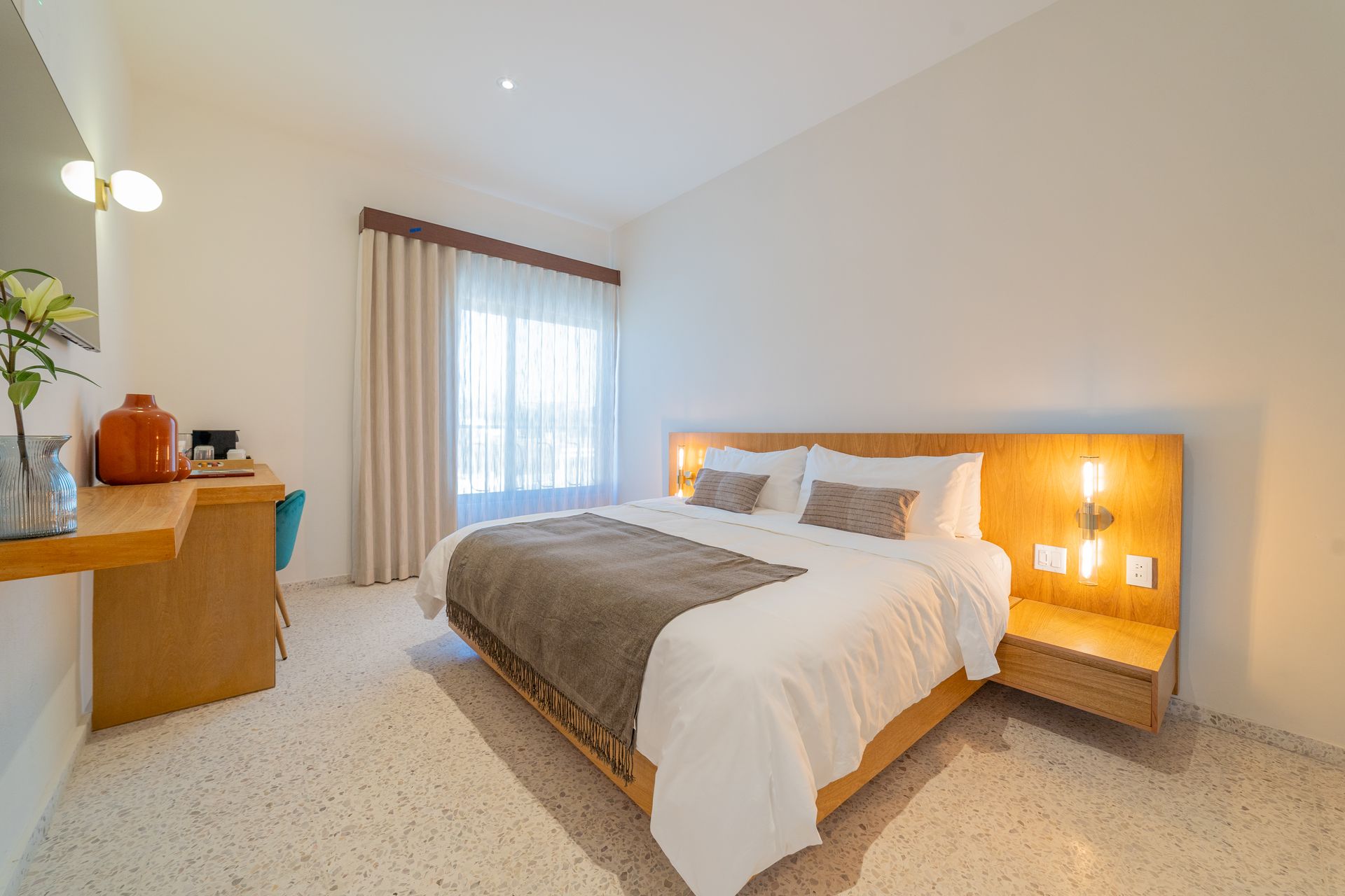 Dormitorio de hotel con cama, escritorio y mesa auxiliar.