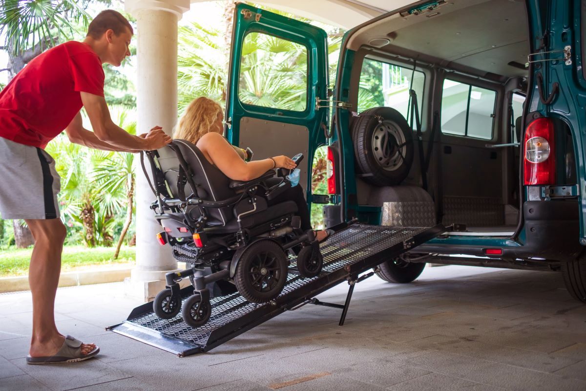 A Man is Helping a Woman in a Wheelchair Into a Van — Supportability Care Services in West Rockhampton, QLD