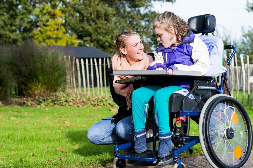 A Woman is Next to a Young Girl in a Wheelchair — Supportability Care Services in West Rockhampton, QLD