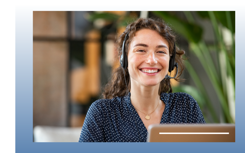 Smiling woman with earbuds on a laptop in a bright office setting