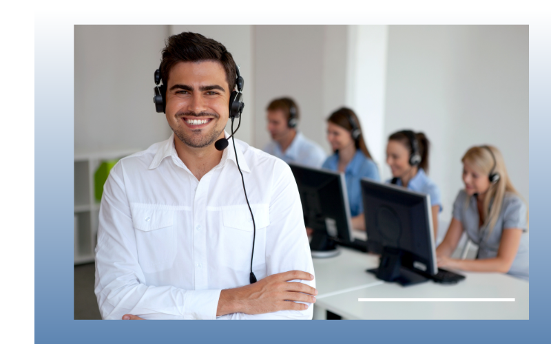 Smiling customer support agent wearing a headset in a bright call center with coworkers at computers