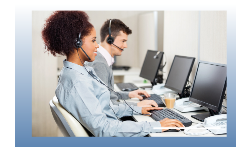 Call center agents wearing headsets typing at desktop computers in an office
