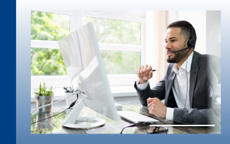 Customer support agent wearing a headset at a desk with a desktop computer in a bright office
