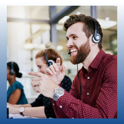 Smiling man in maroon shirt wearing headphones, speaking and gesturing in a modern office setting