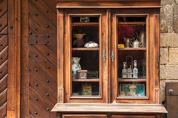 A wooden display cabinet with glass doors, filled with various vintage kitchenware and decorative items.