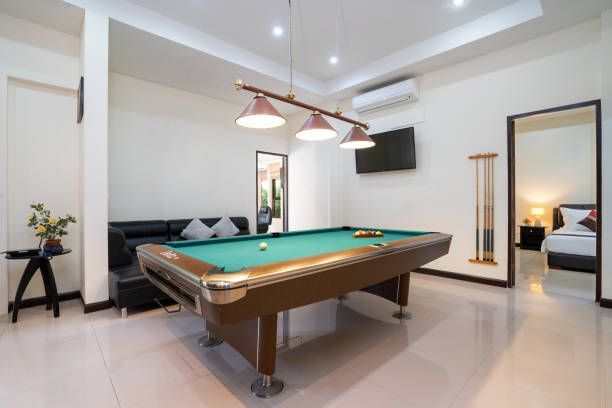 Pool table in a room with a black couch, overhead lights, and a doorway to a bedroom.