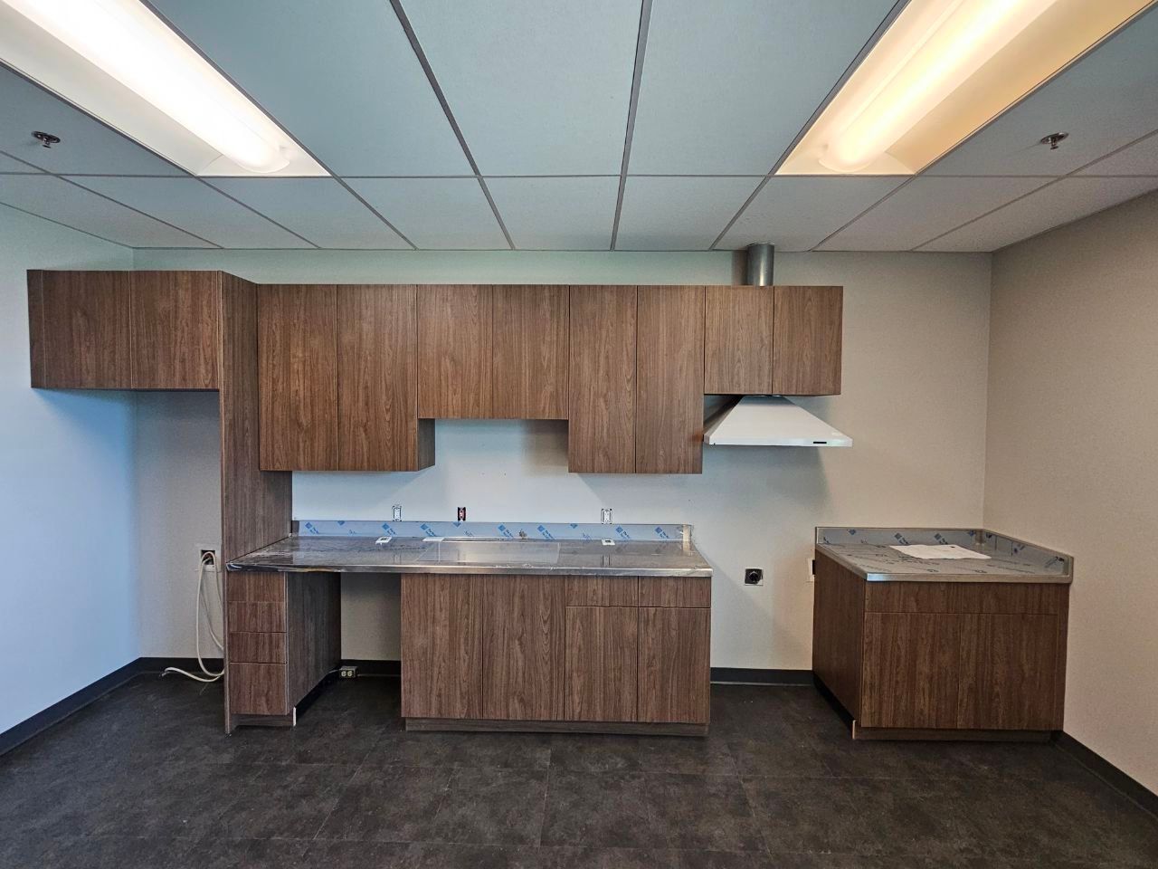 Kitchen with brown cabinets, stainless steel countertops, and a white range hood.