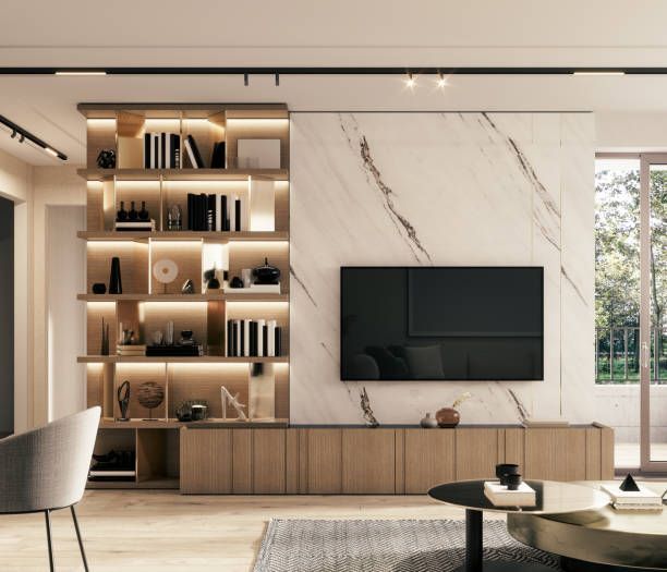 A modern living room with a wall-mounted TV on a white marble backdrop, a wooden media console, and a lighted bookshelf.