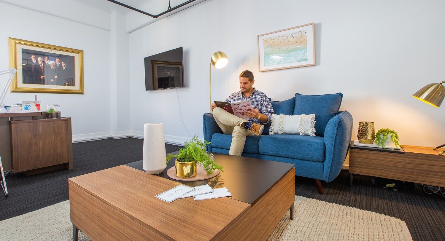 A man is sitting on a blue couch in a living room.