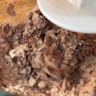 Un piatto bianco viene versato in una ciotola di cioccolato in polvere.