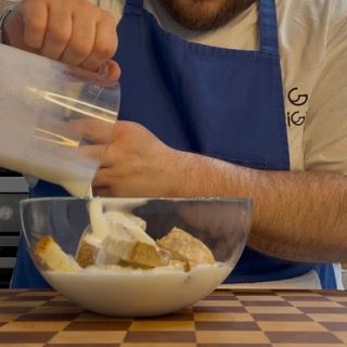 Un uomo con un grembiule blu sta versando il latte in una ciotola di cibo
