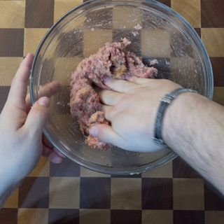 Una persona sta mescolando la carne in una ciotola di vetro