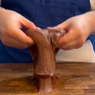 Una persona sta stendendo un pezzo di cioccolato su un tagliere.