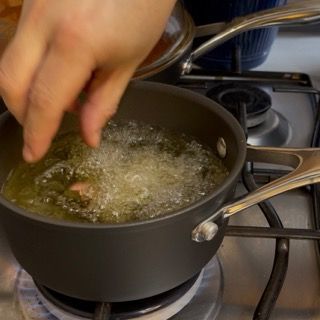 Una persona sta versando l'olio in una pentola su un fornello