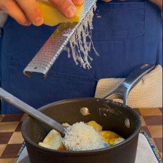 Una persona che grattugia il formaggio in una pentola con un cucchiaio