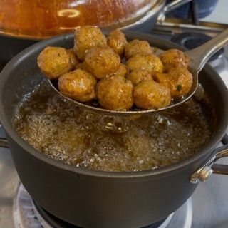 Un cucchiaio di polpette viene versato in una pentola di acqua bollente