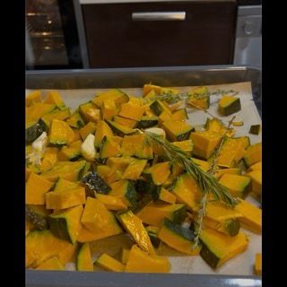 Pezzi di zucca in una teglia con olio, sale, aglio e rosmarino