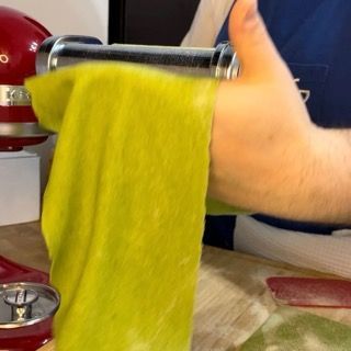 Sfoglia di pasta verde molto sottile su un piano di lavoro.