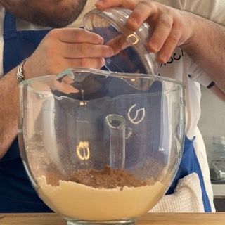 Un uomo sta versando del liquido in una ciotola di vetro con il numero 9 sopra