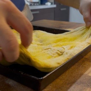 Pizza condita con olio e sale in fiocchi prima della cottura
