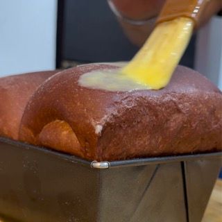 Una pagnotta di pane viene spennellata con il burro