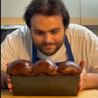 Un uomo con un grembiule tiene in mano una pagnotta di pane