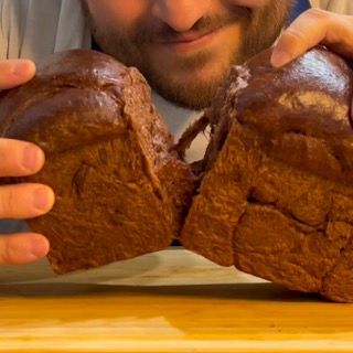 Un uomo tiene in mano due pezzi di pane al cioccolato.