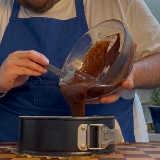 Un uomo che versa un liquido marrone in una tortiera